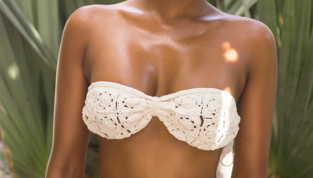White crochet bikini top worn by a person with a blurred natural background