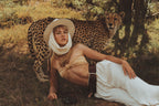 Woman in a safari outfit with a cheetah in a natural setting