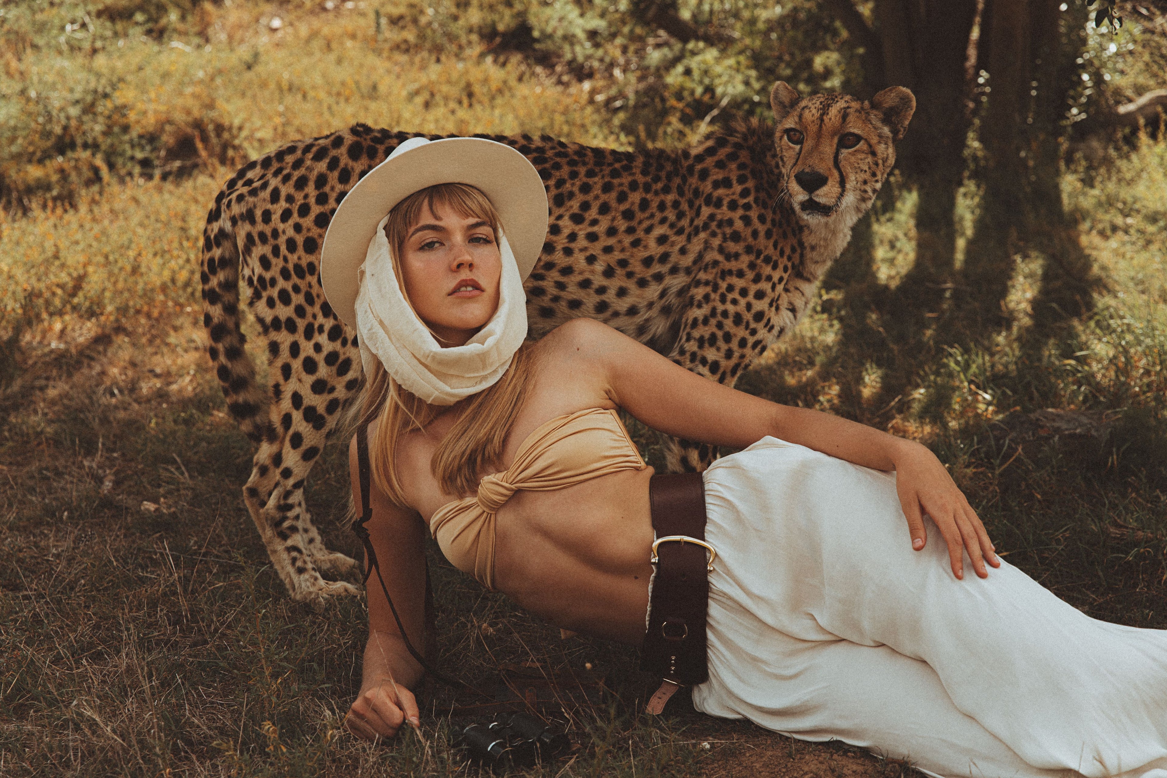 Woman in a safari outfit with a cheetah in a natural setting