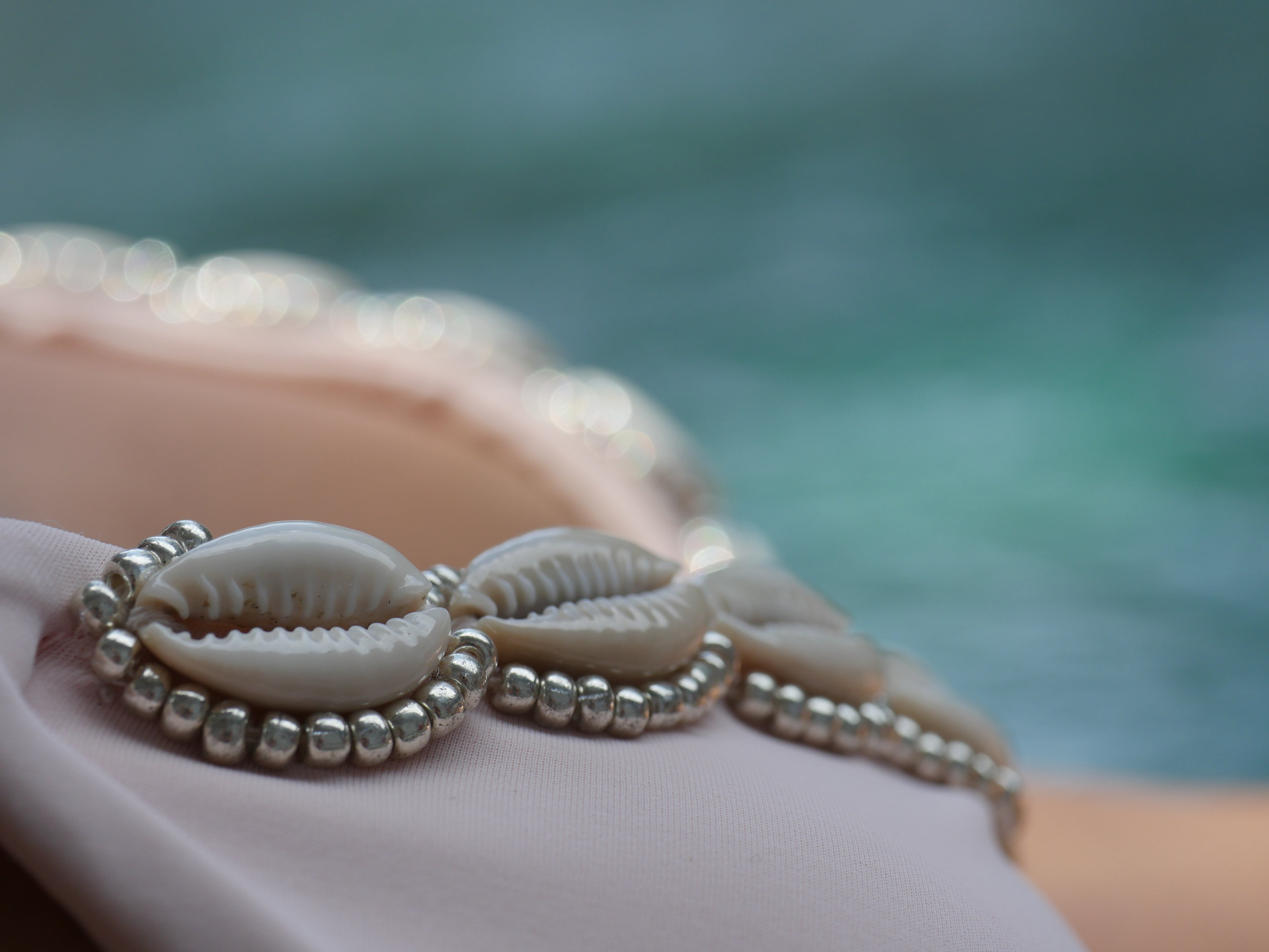 Shell and bead bikini top detail with a blurred natural background