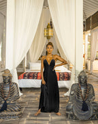 Woman in a black dress standing between two statues in a bedroom setting