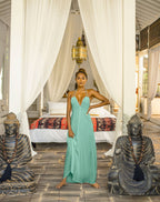 Woman in a aqaumarine dress standing between two Buddha statues in a bedroom setting.